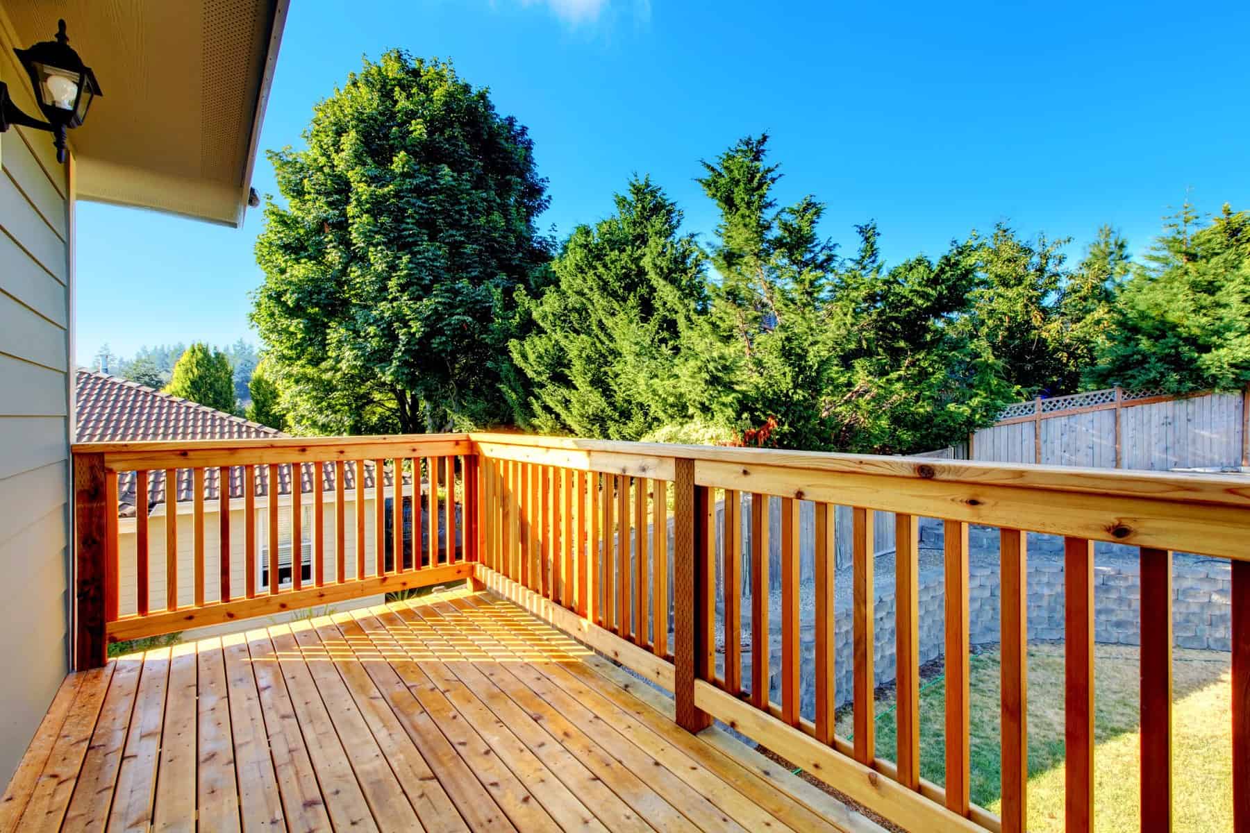 Cedar Stained Residential Deck Warm honey-toned cedar deck with natural wood railings and balusters, adjoining residential home exterior.