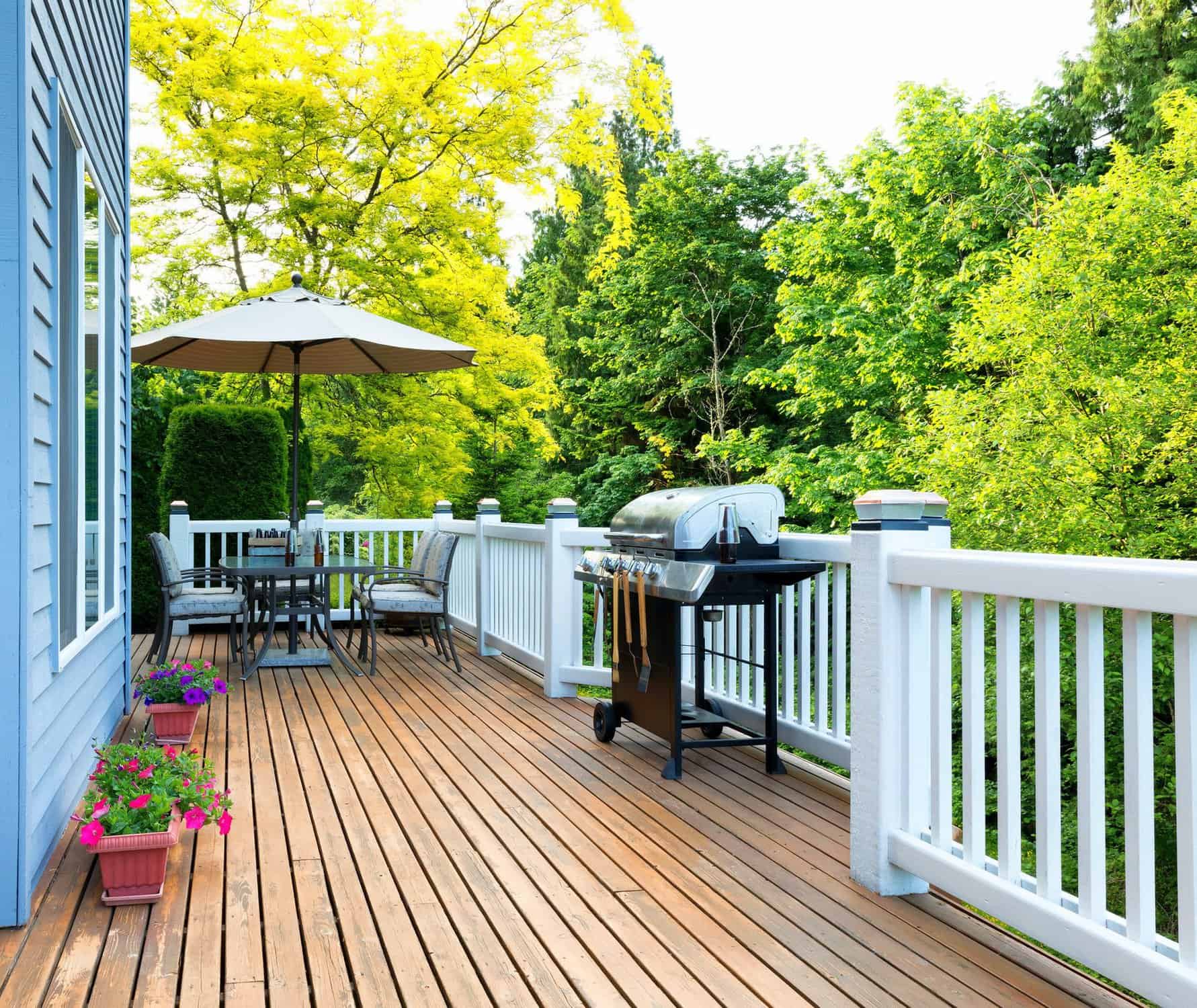 Cedar Deck Painting Nashville Warm cedar-toned painted deck with white vinyl railings, outdoor furniture, and grill in Nashville