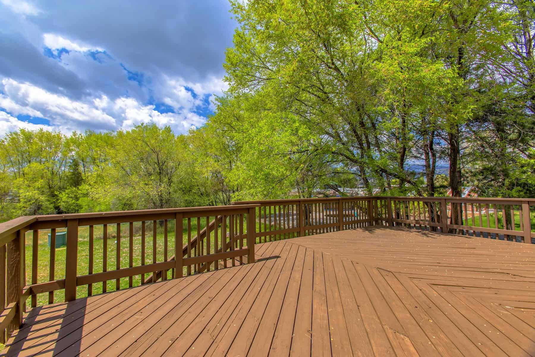 Cedar Stained Residential Deck Warm cedar-stained wooden deck with dark wood railings overlooking tree-lined property in Nashville.