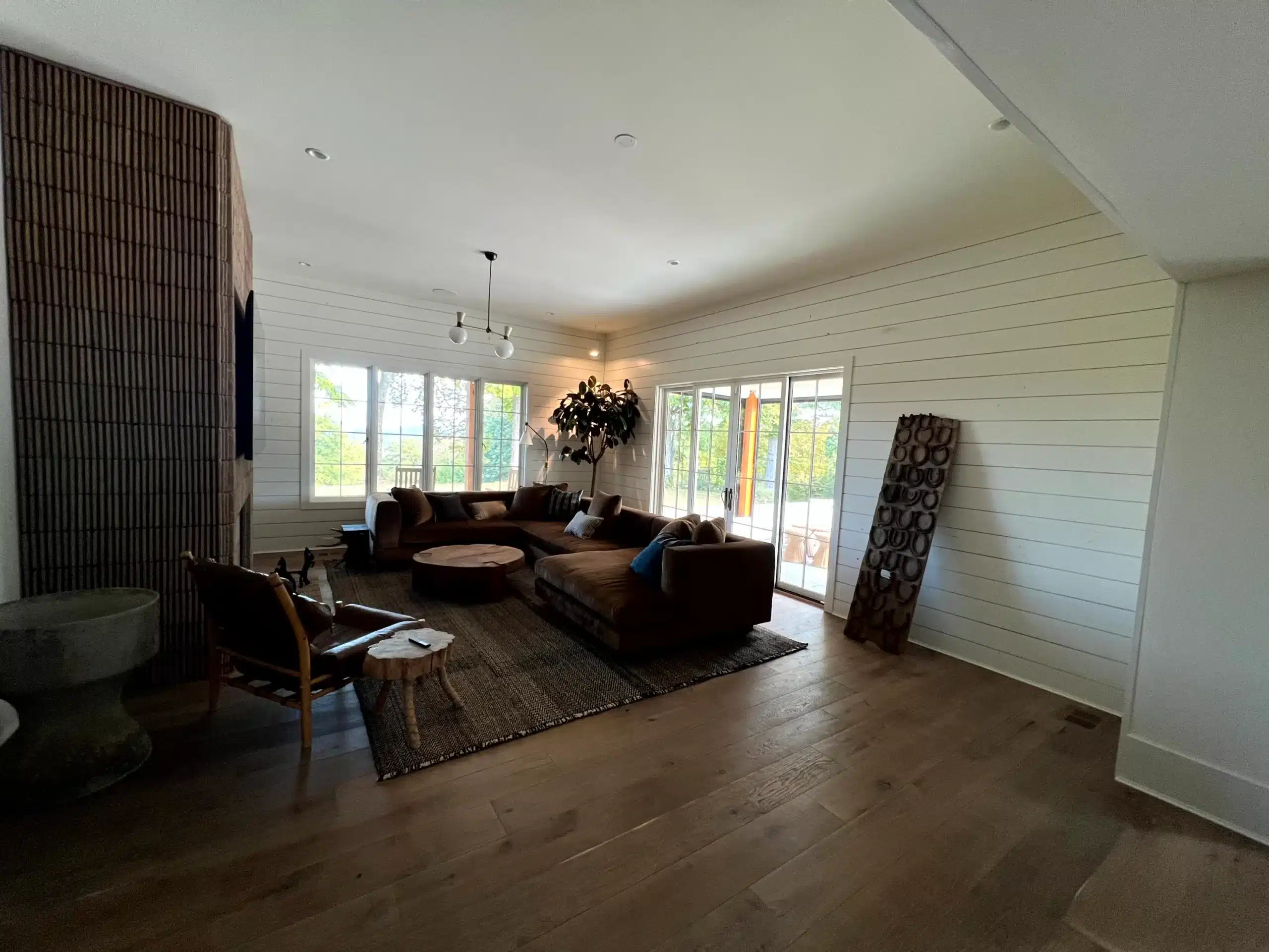White Shiplap Living Room Interior White-painted shiplap walls with cream ceiling, dark wood flooring, and multi-pane glass doors in modern residential living