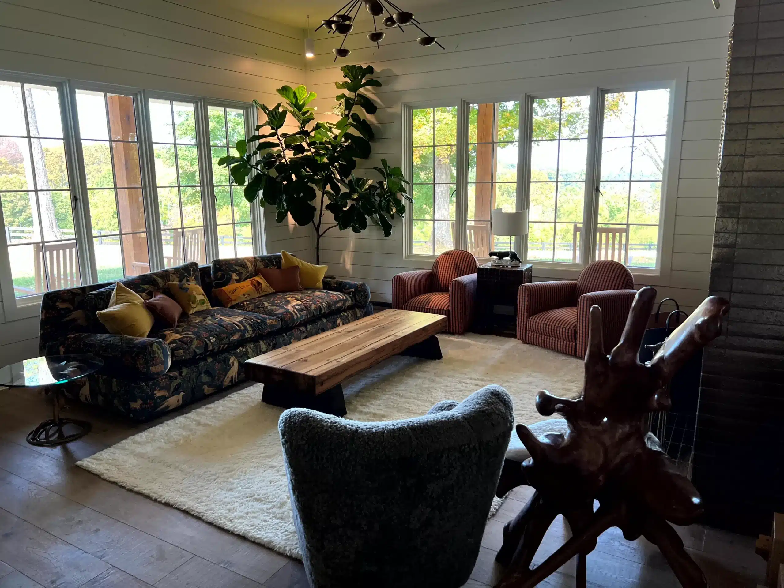White Shiplap Living Room Interior White painted shiplap walls and ceiling in bright sunroom with expansive multi-pane windows, wood flooring, and modern