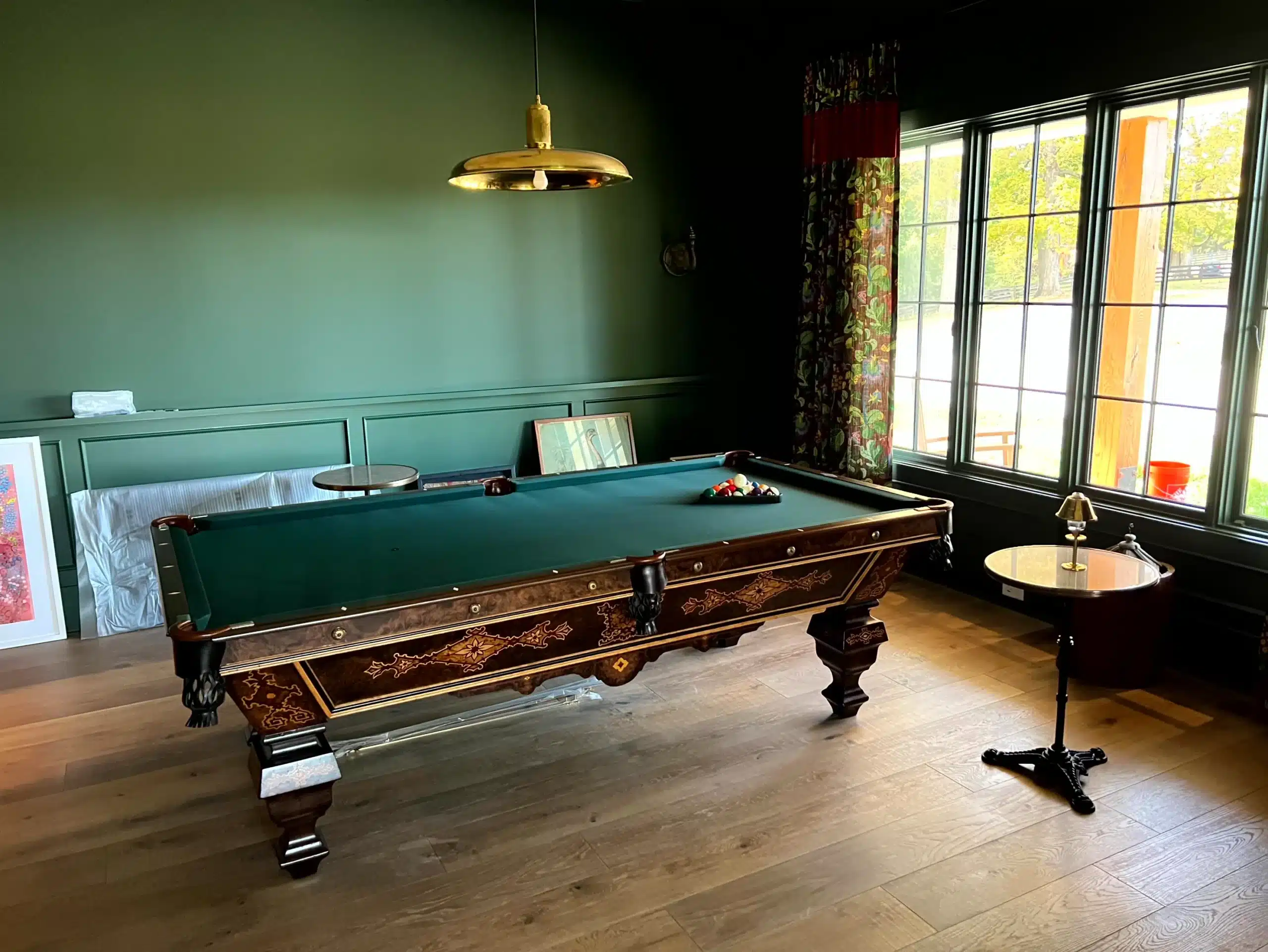 Sage Green Billiards Room Sage green painted walls with wainscot paneling in residential billiards room with pool table and gold pendant light