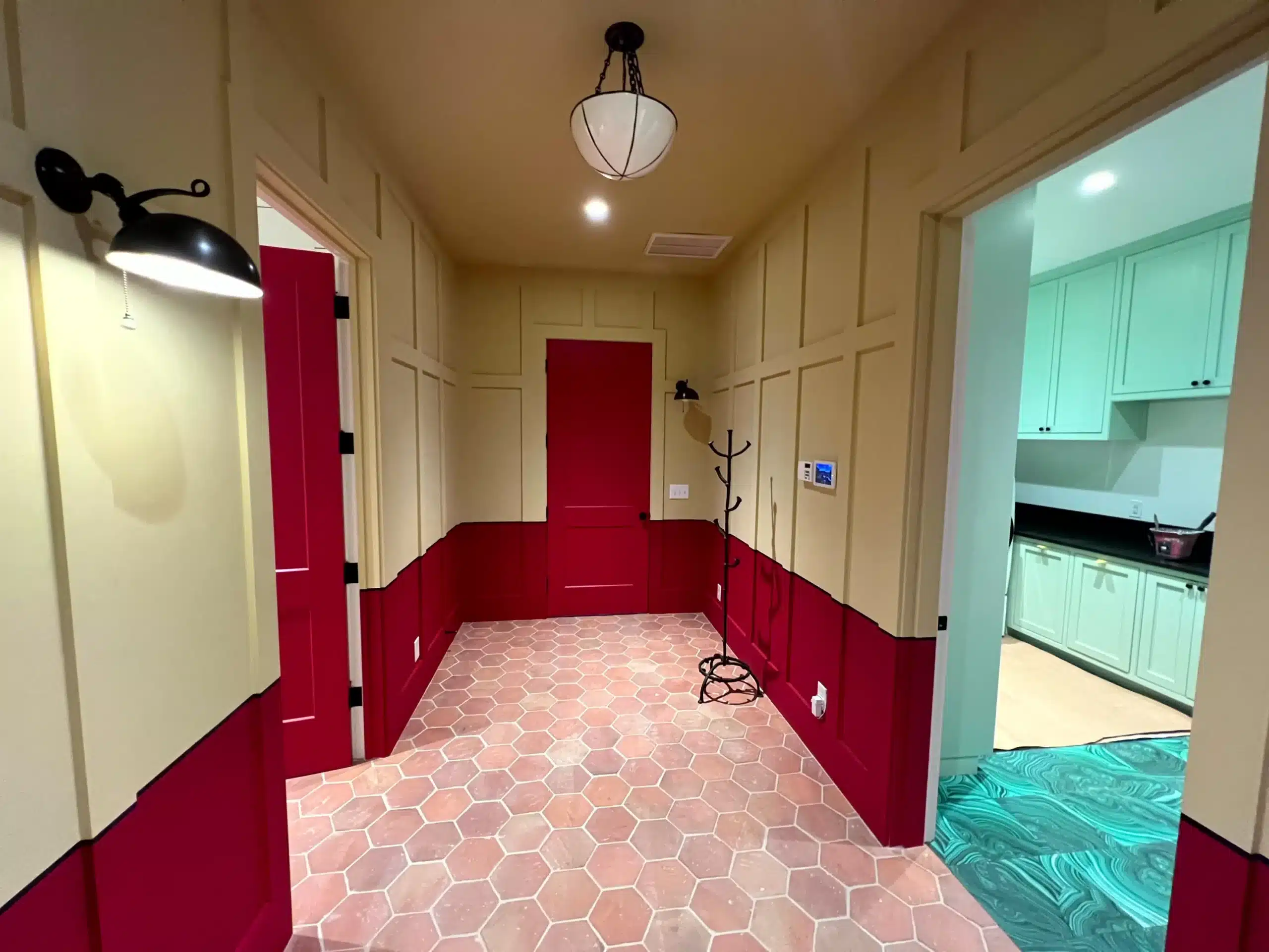 Red And Cream Interior Hallway Painting Cream-painted hallway with deep red wainscot and doors, hexagonal tile flooring, and pendant lighting during interior