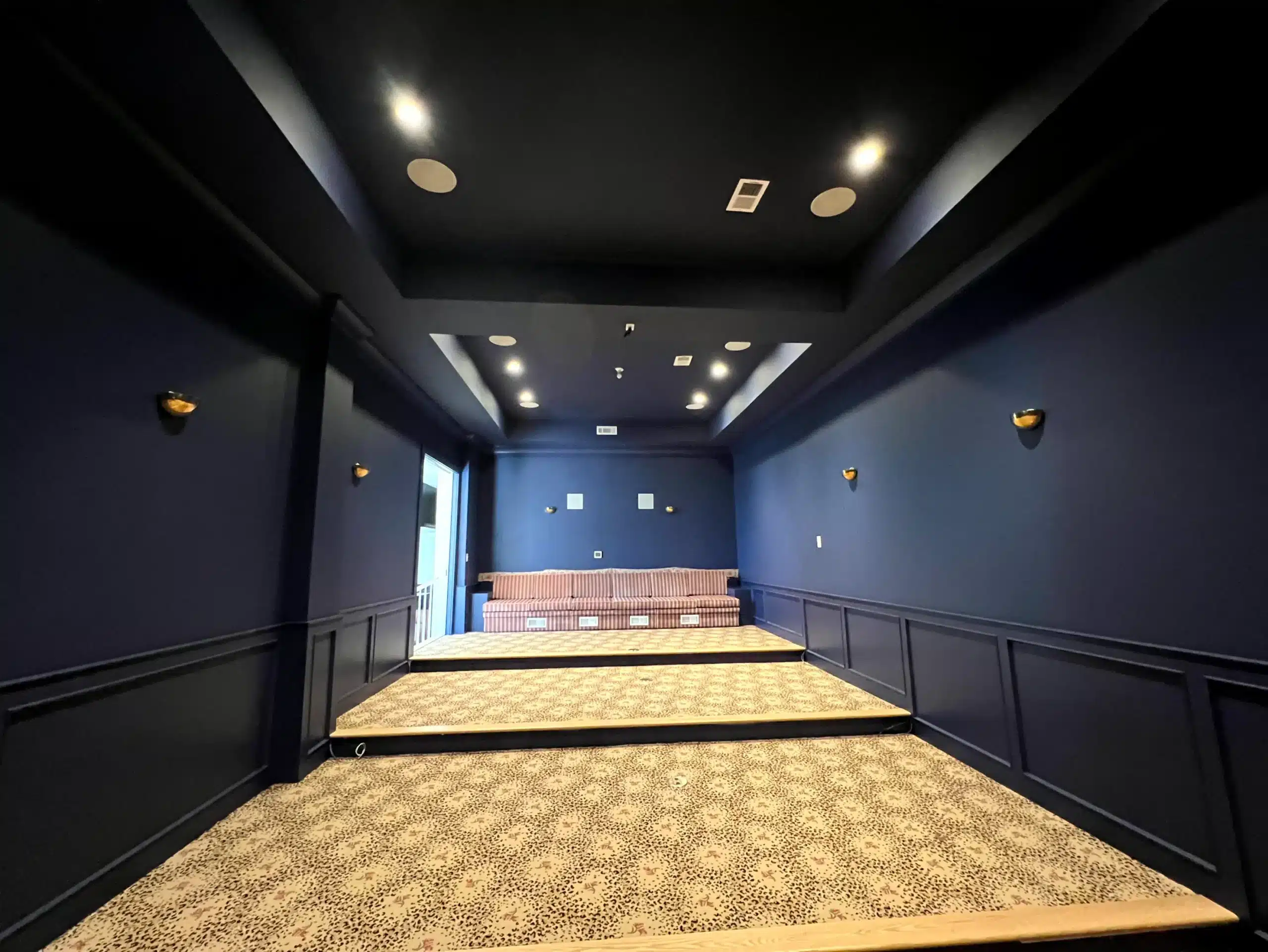 Navy Blue Commercial Hallway Interior Navy blue painted commercial hallway with black wainscot paneling, recessed lighting, and gold wall sconces