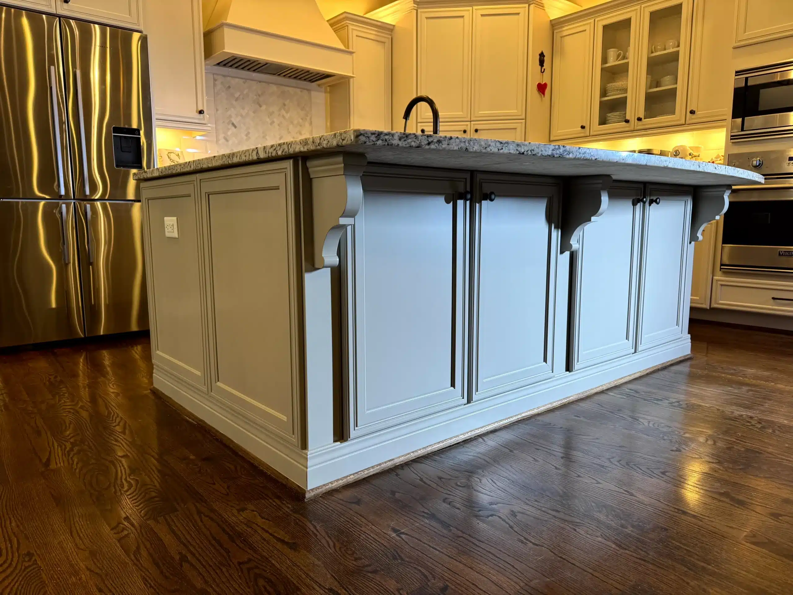 Cream And White Kitchen Island Cabinets Cream and white painted kitchen island with dark granite countertop and black hardware in residential kitchen.