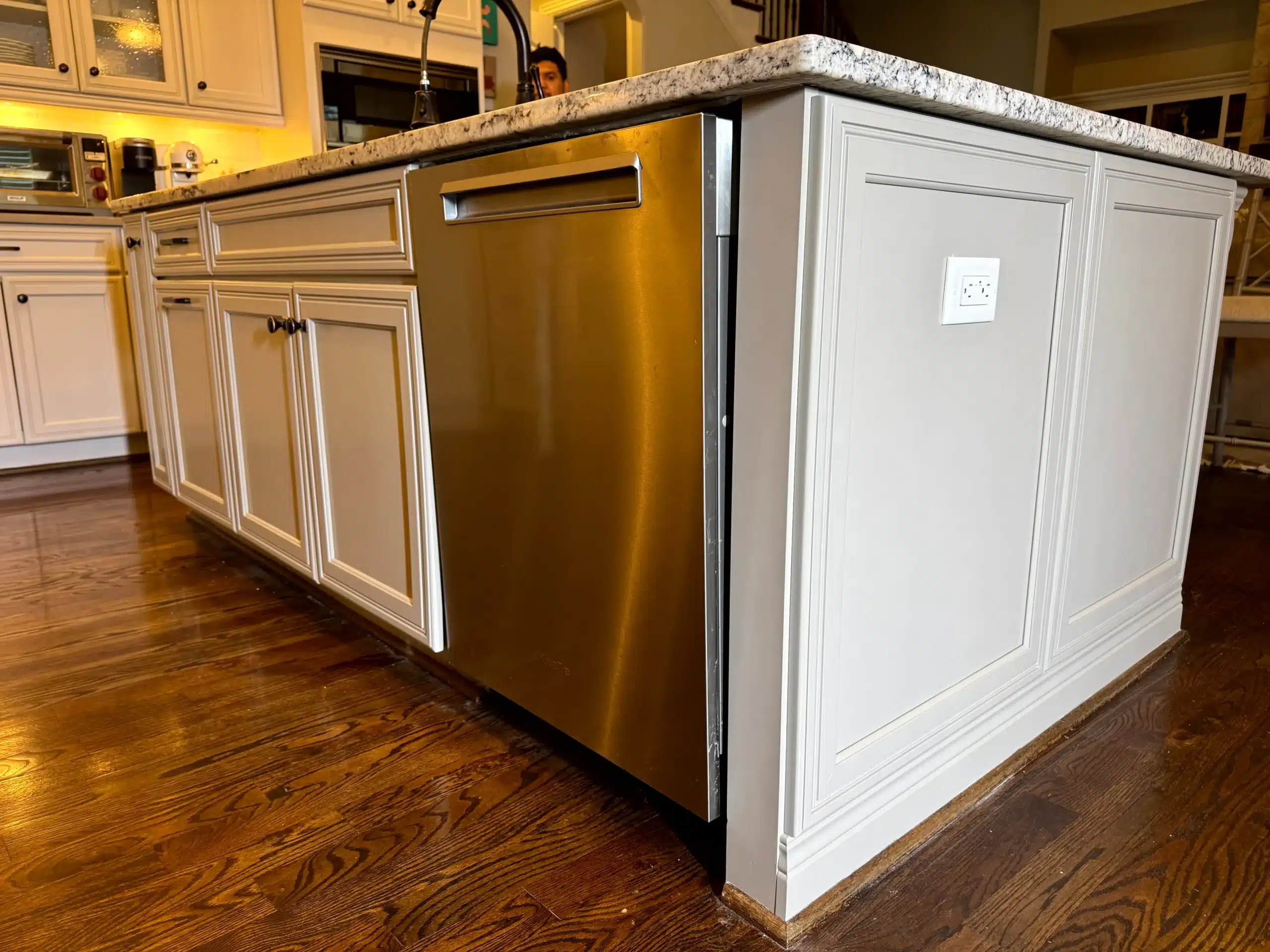 White Painted Kitchen Cabinets White-painted kitchen island cabinetry with speckled granite countertop and stainless steel appliance on wood flooring.