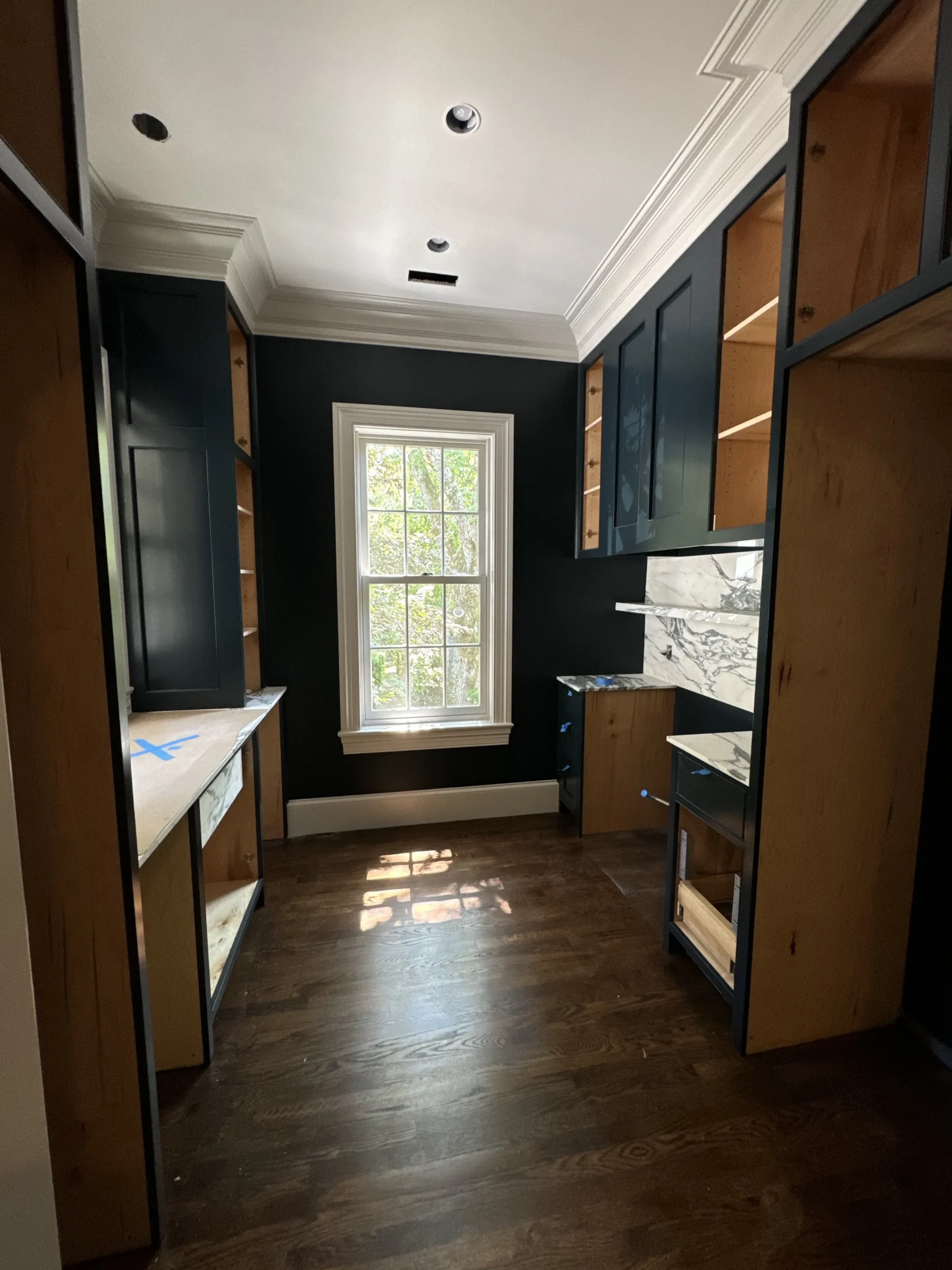 Navy Blue Cabinet Painting Navy blue painted cabinetry with wood interiors and marble countertops in residential walk-in closet during interior