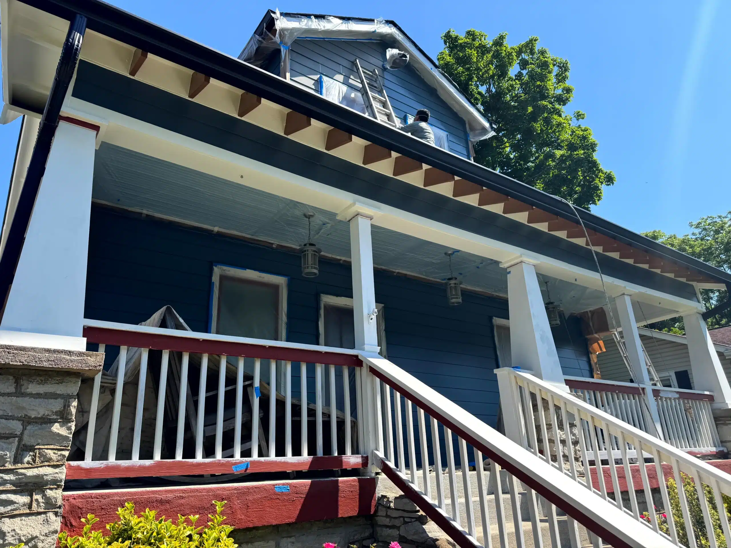 Red and White Painted Porch Exterior Red-painted front porch base with white railings and columns on residential exterior during painting project in Nashville