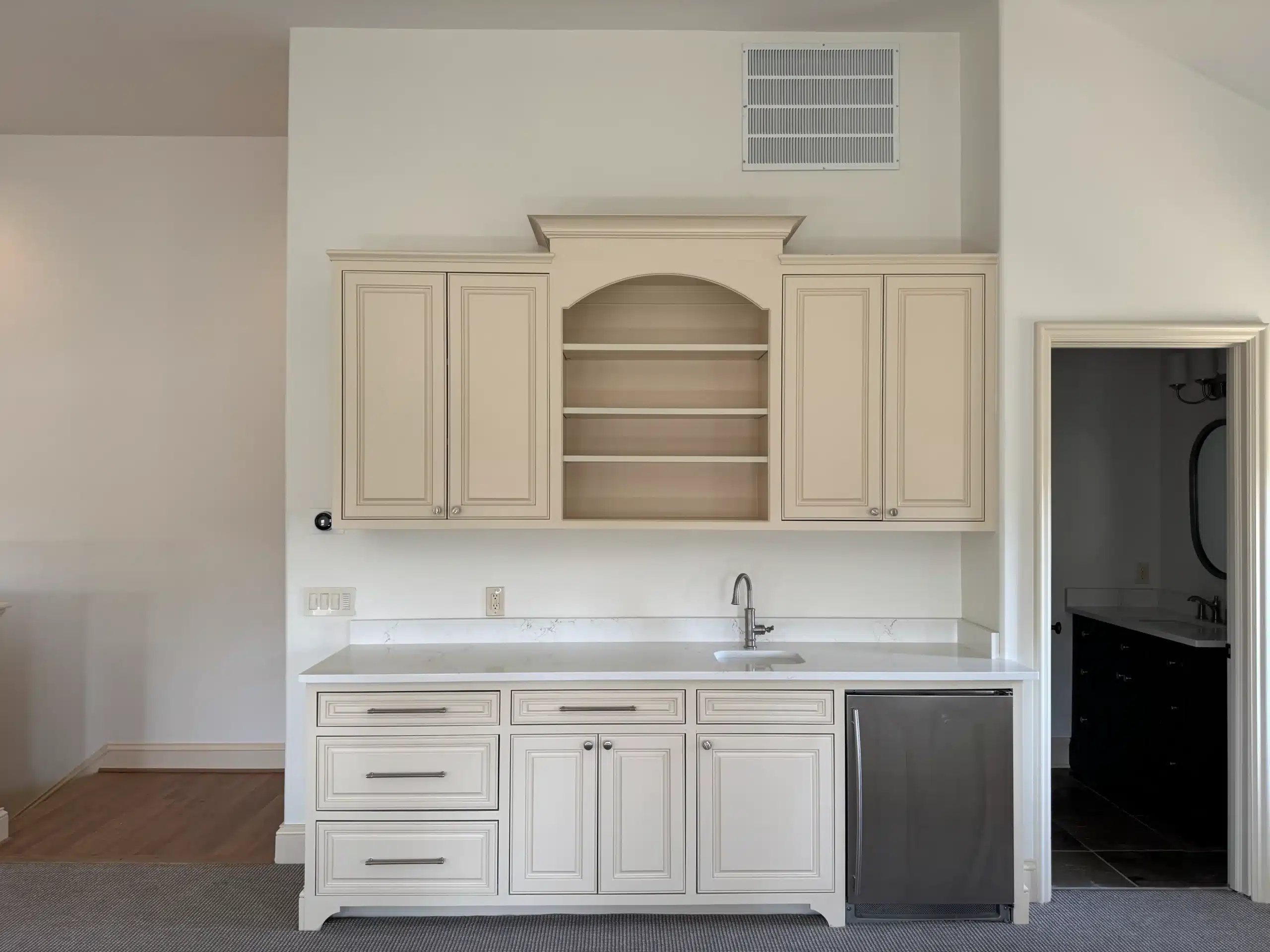 Cream Cabinet Painting Kitchen Cream-painted kitchen cabinetry with arched open shelving, white countertop, stainless steel sink, and dark dishwasher
