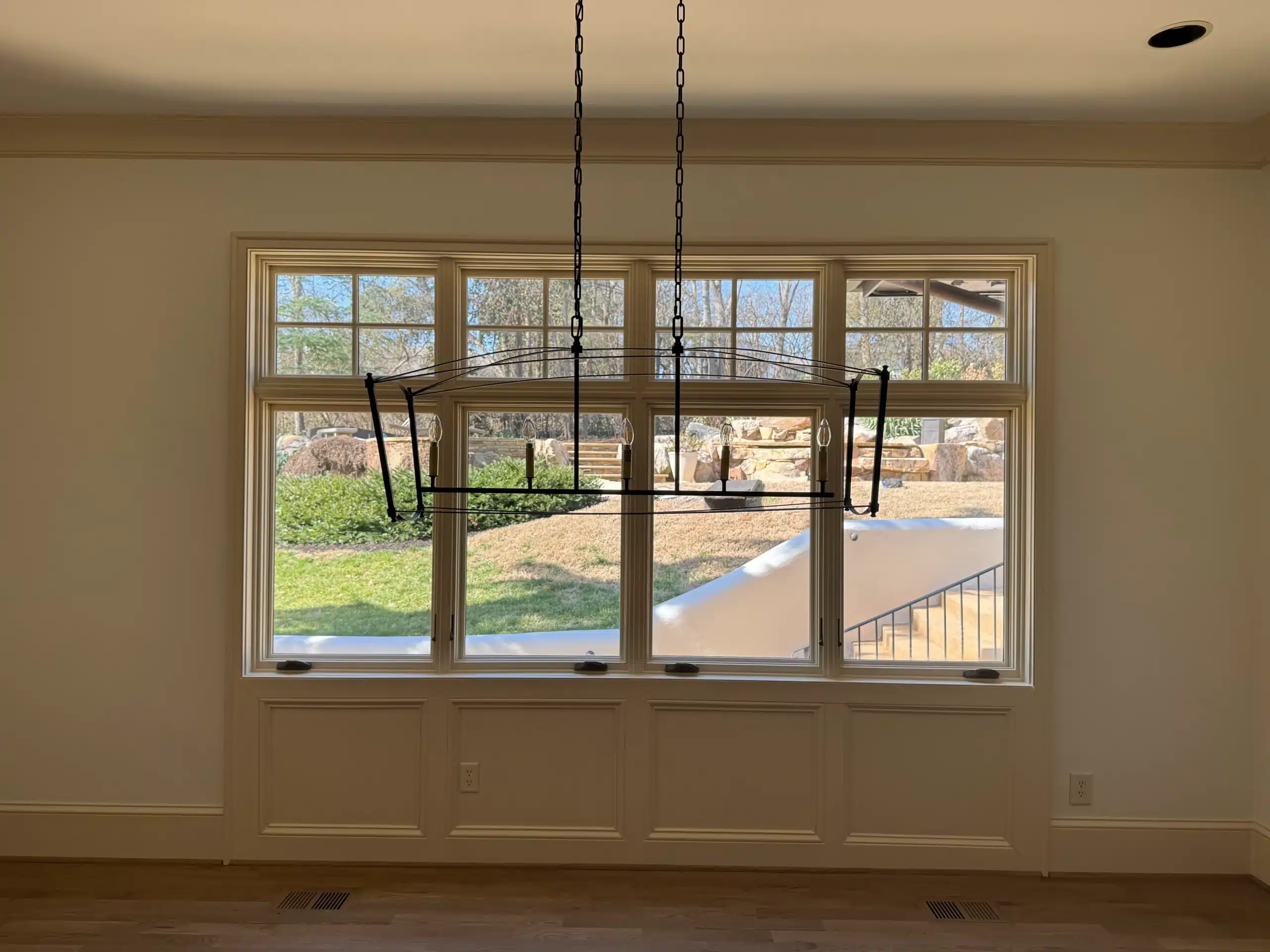 Cream Interior Wall With Wood Trim Cream-painted interior wall with wood-framed windows and black pendant lighting fixtures in residential home
