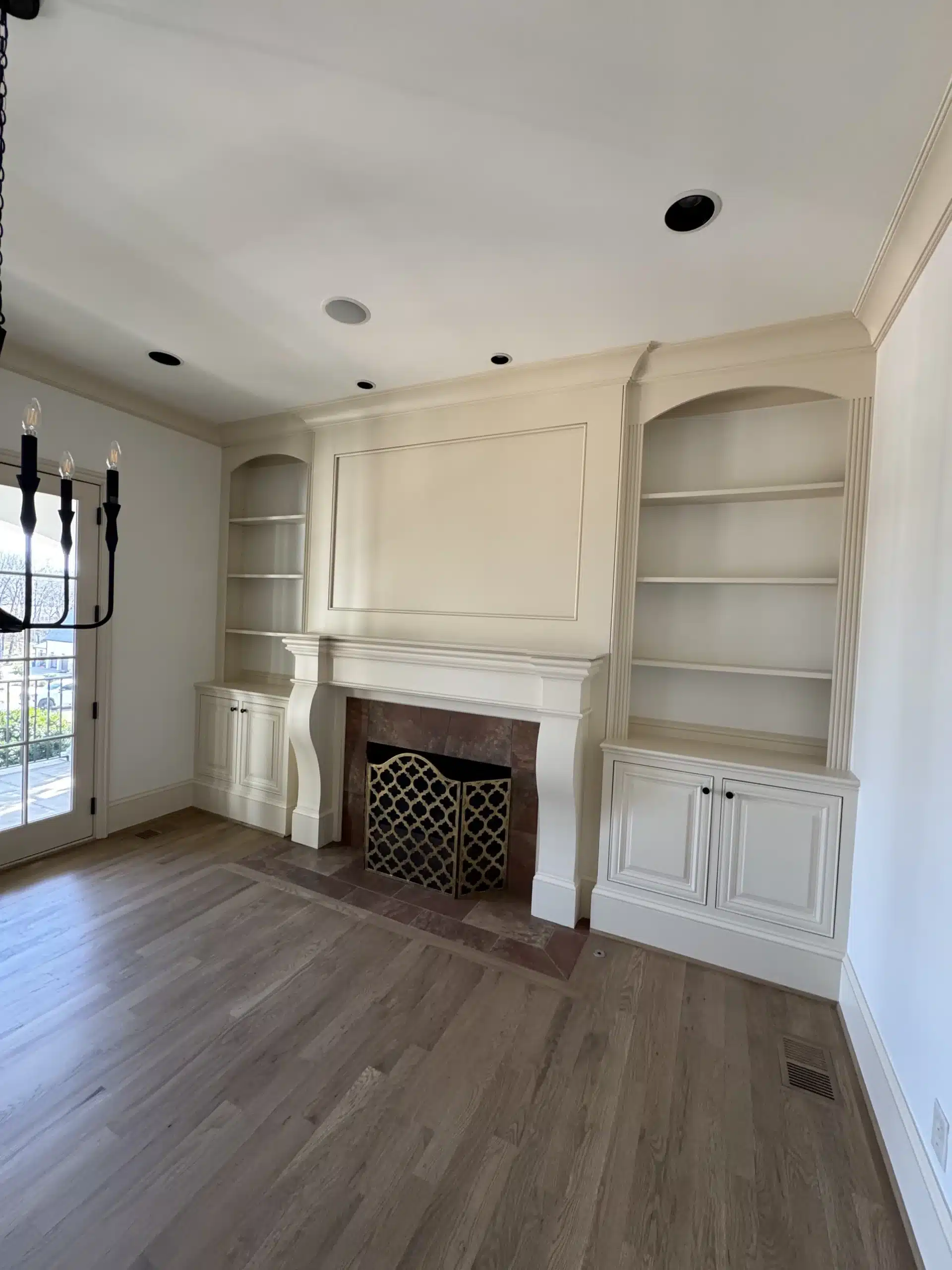 Cream Painted Living Room Built-Ins Cream-painted built-in cabinetry with arched shelving, fireplace surround, and recessed ceiling lights in residential living